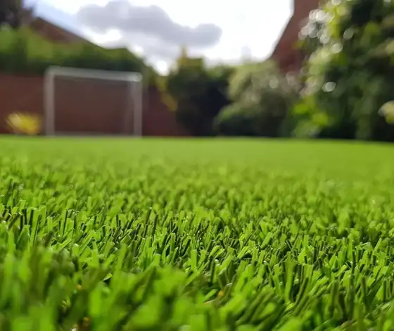 Pasto sintético en un jardín con portería de futbol al fondo