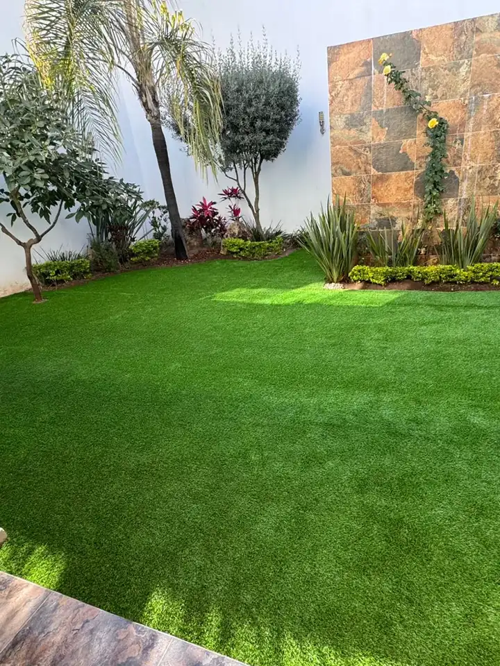 Pasto sintético Viena 30 instalado: jardín con muro de piedra