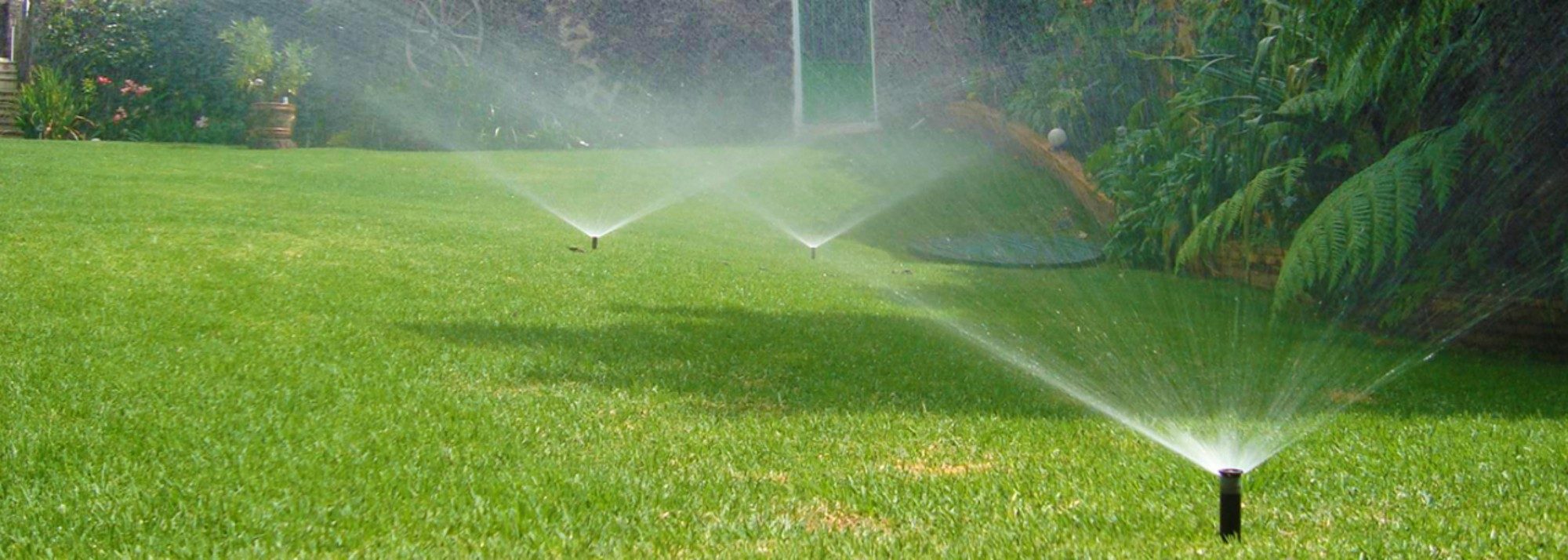 Sistema de riego automático en operación - múltiples aspersores cubriendo jardín en Tampico